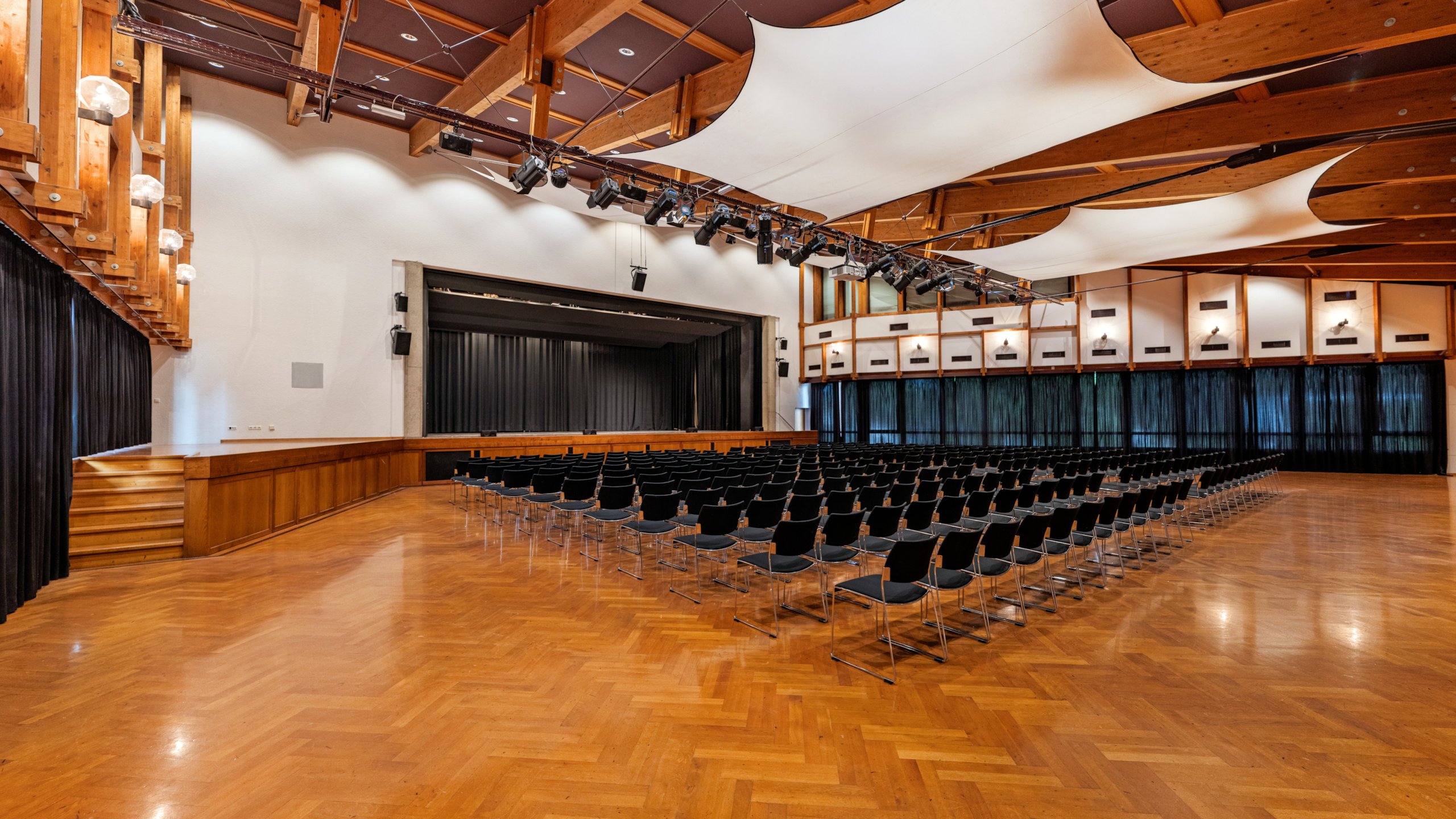 Das Bild zeigt den Großen Saal im Hofsteigsaal in Lauterach mit Reihenbestuhlung und Bühne.