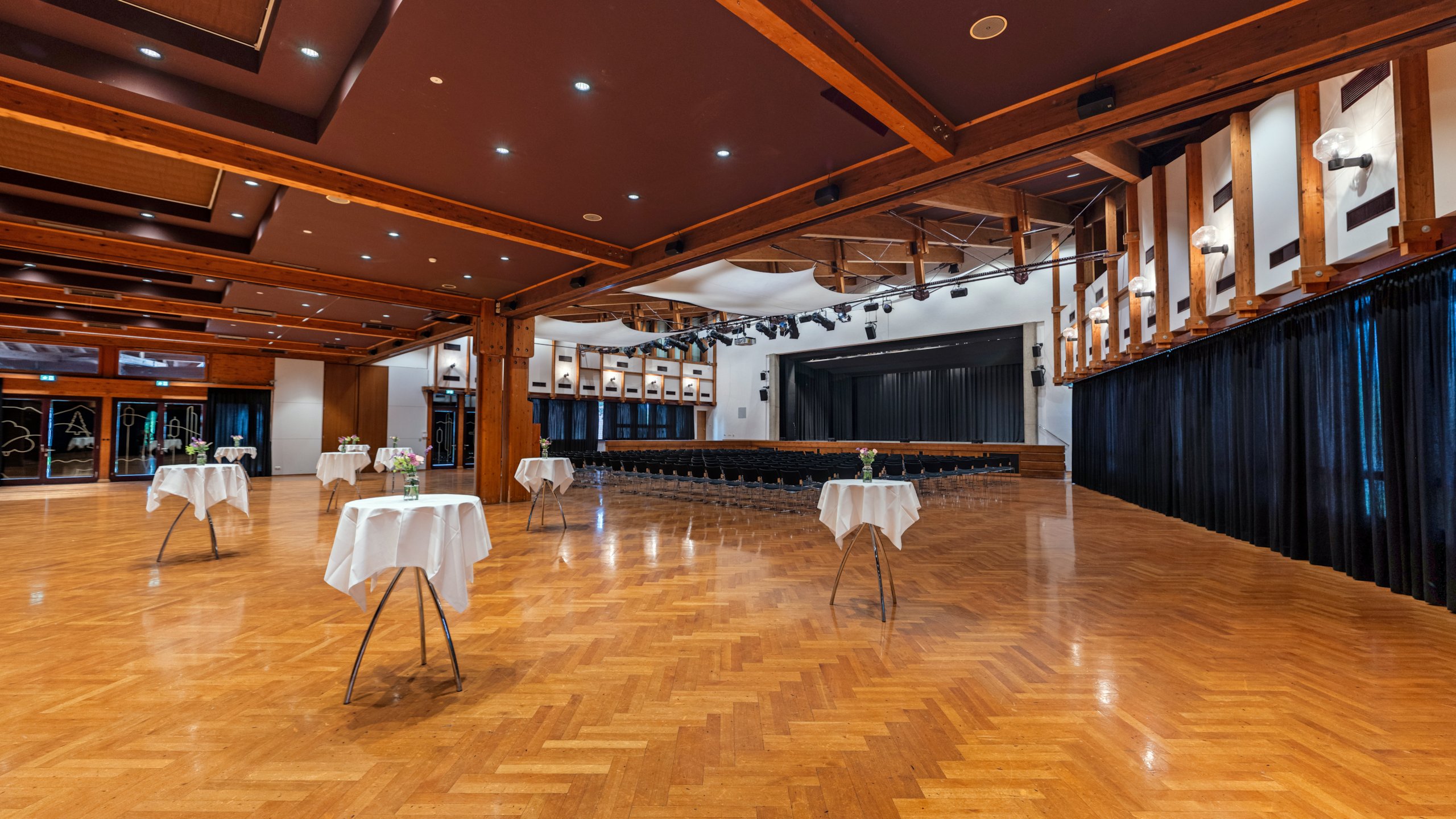 Das Bild zeigt den Großen Saal im Hofsteigsaal in Lauterach mit Reihenbestuhlung, Stehtischen und Bühne.