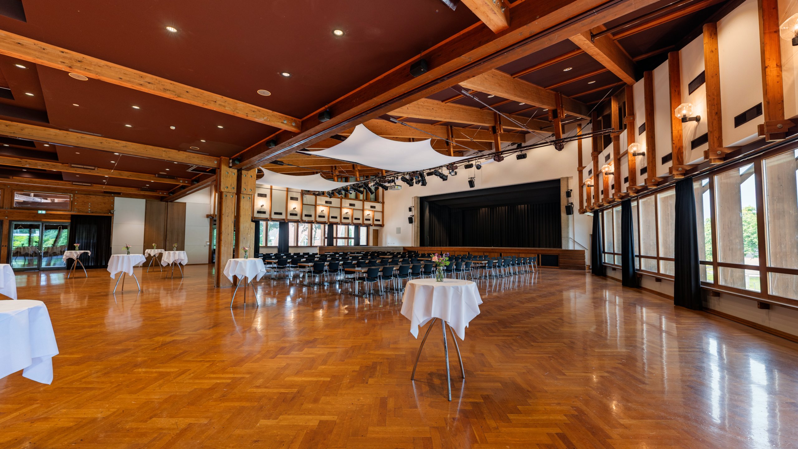 Das Bild zeigt den Großen Saal im Hofsteigsaal in Lauterach mit Bankettbestuhlung, Stehtischen und Bühne.