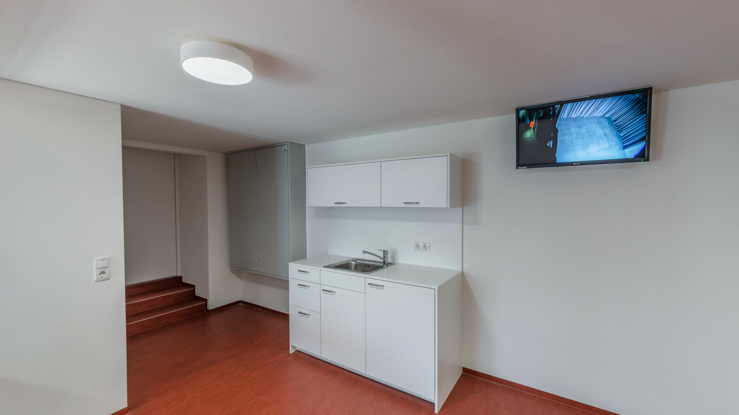 Das Bild zeigt den Backstage-Bereich im Lauteracher Vereinshaus mit einer Küchenzeile und einem Monitor.