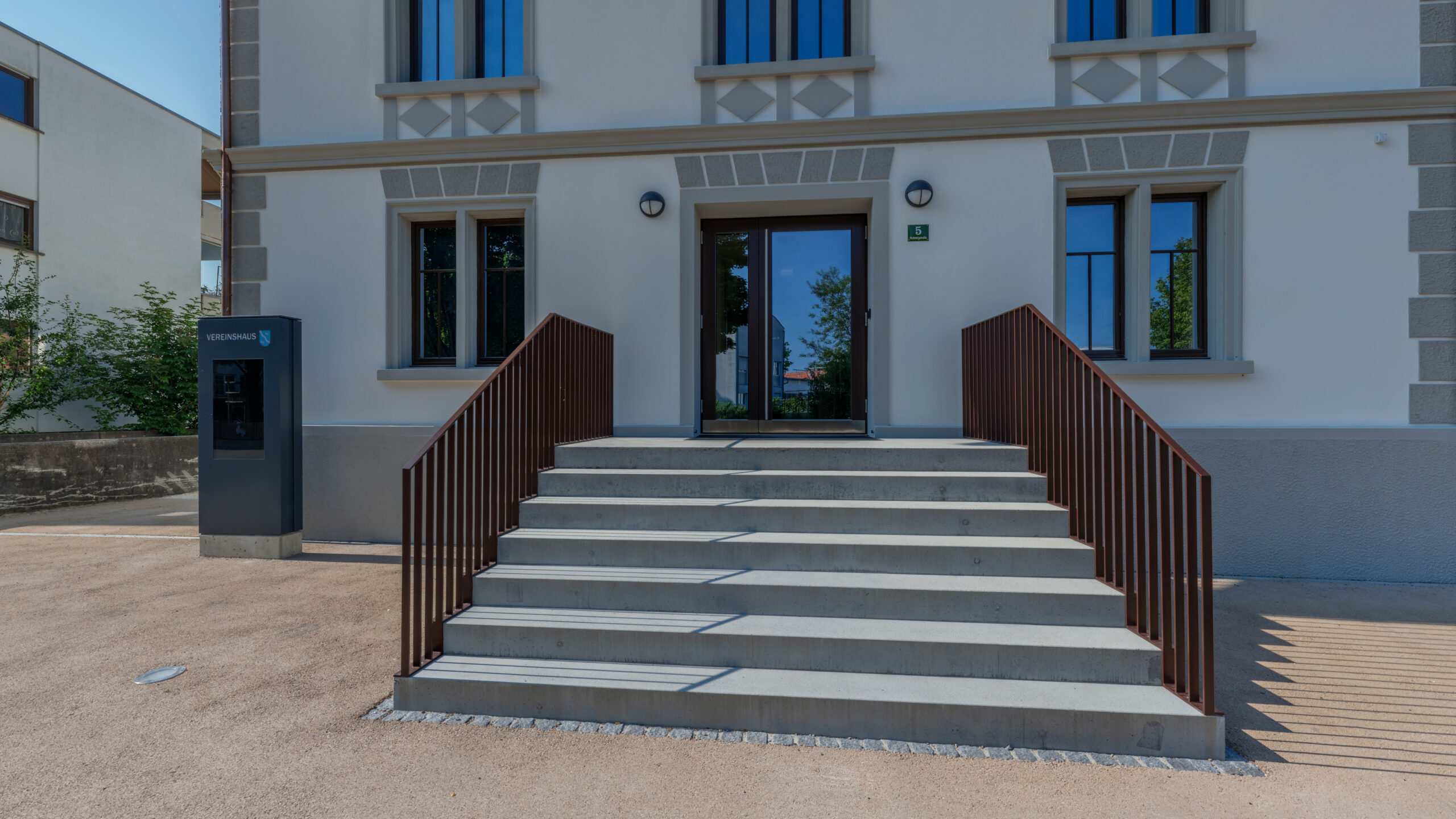 Das Bild zeigt den Haupteingang des Vereinshauses mit Stufen und Geländer.