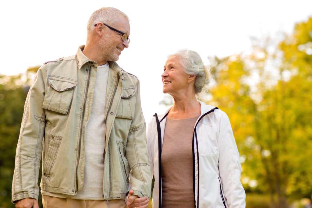 Ein Senior und eine Seniorin schauen sich an und halten Hände.