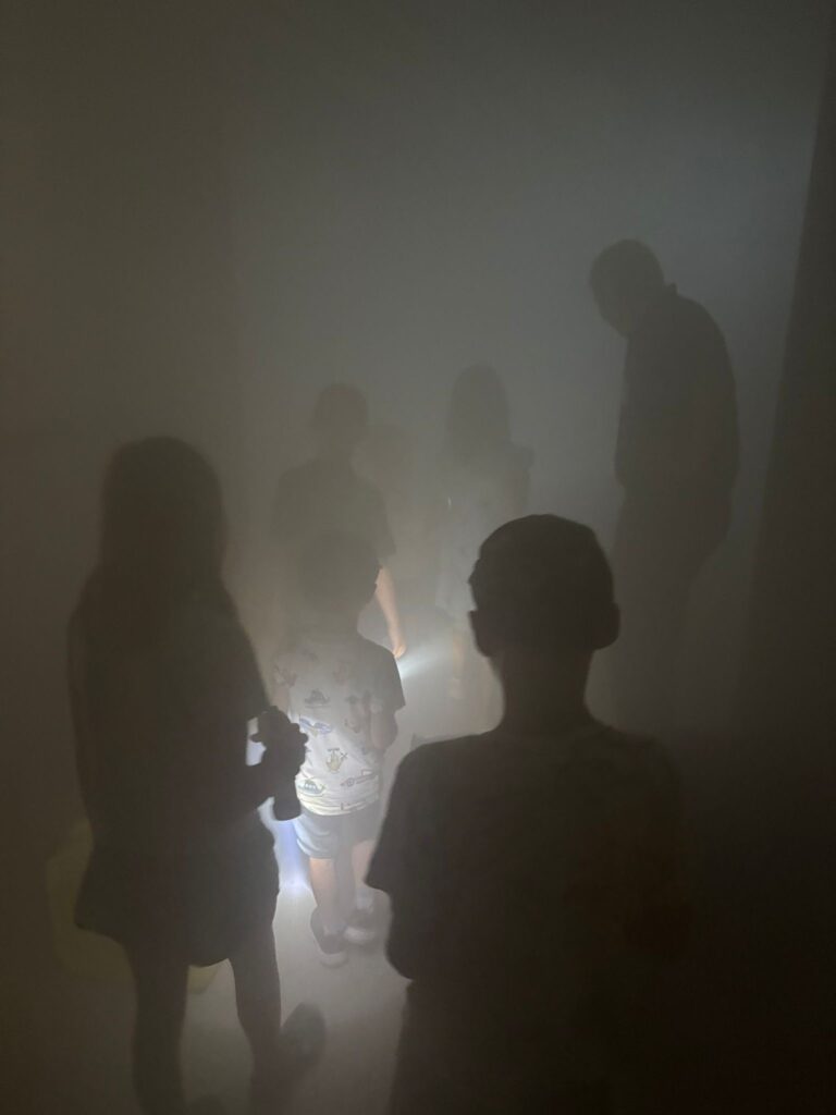 Das Bild zeigt eine Gurppe von Kindern in einem Raum voller Nebel bei einer Feuerwehrbesichtigung.