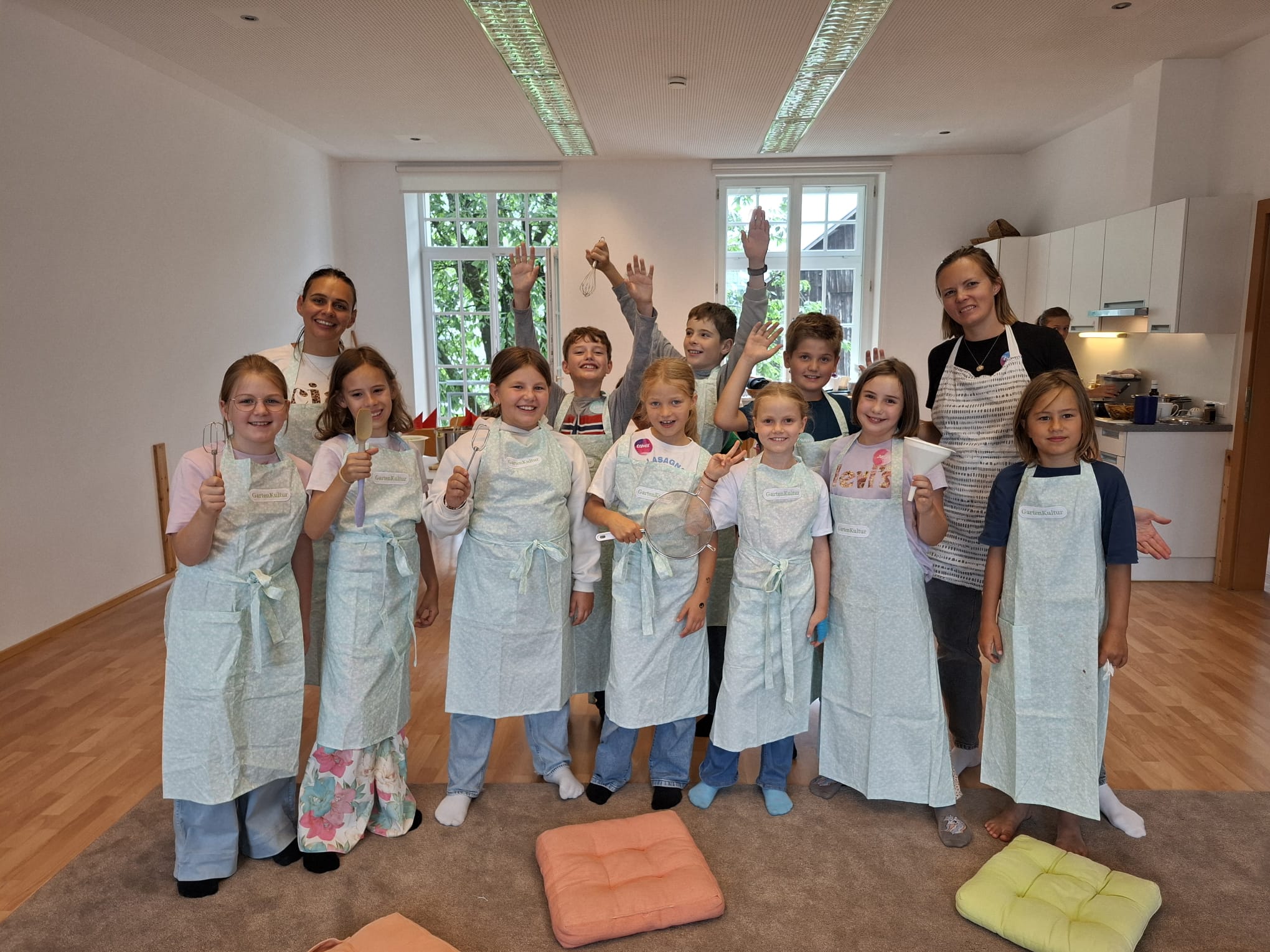Das Kind zeigt eine Gruppe von Kindern beim Familienfrühstück. Sie alle tragen Kochschürzen.