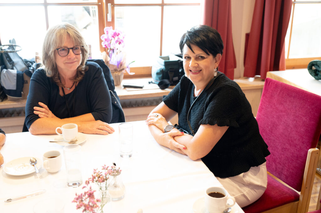 Das Bild zeigt zwei Frauen an einem Tisch, eine davon Vizebürgermeisterin Sabine Kassegger, mit Kaffeetassen, beide lächeln in die Kamera.