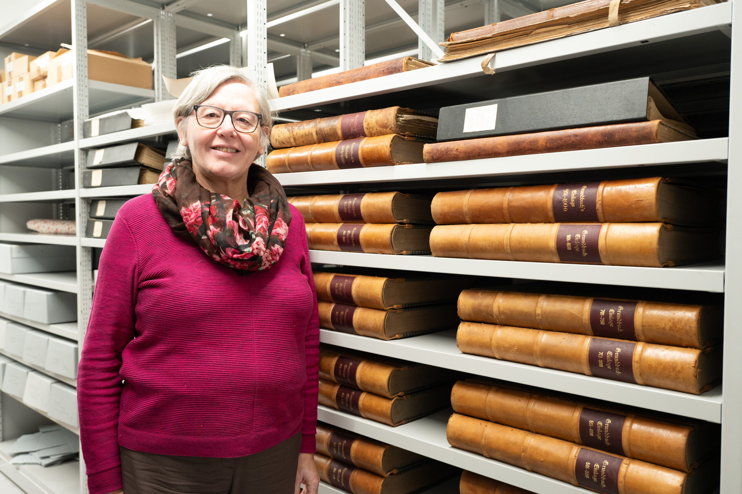 Das Bild zeigt eine Frau vor einem Regal im Lauteracher Gemeindearchiv, das mit historischen Büchern gefüllt ist.