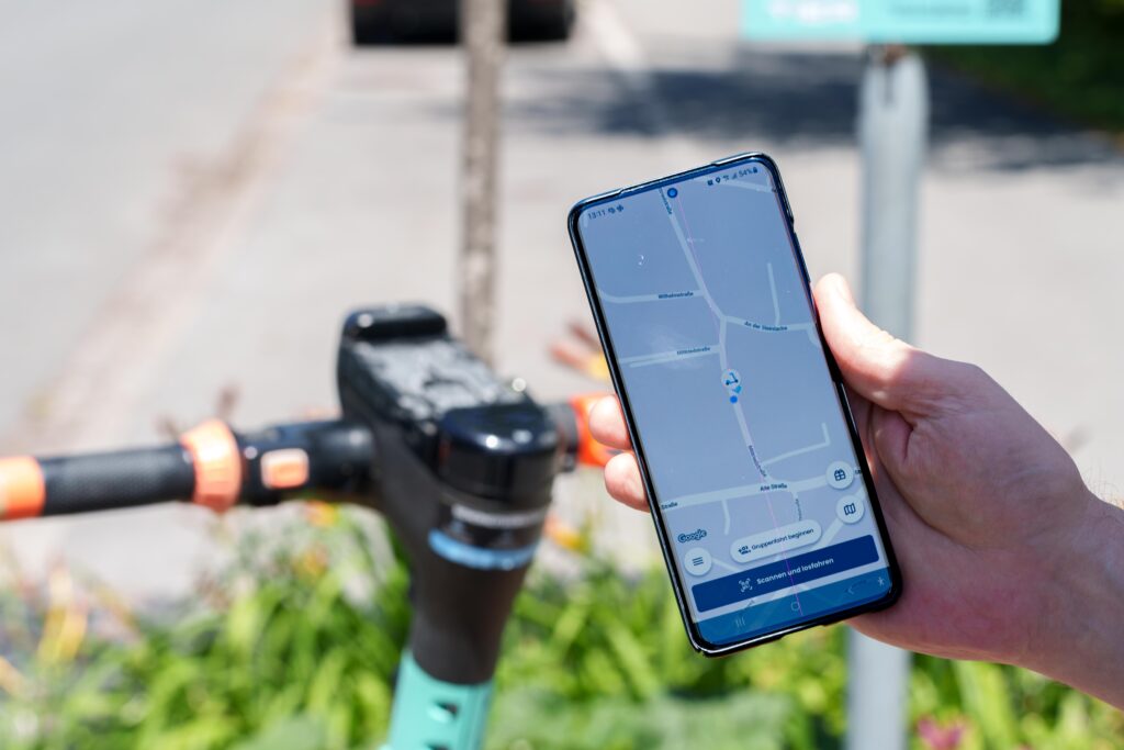 Das Bild zeigt eine Hand, die ein Smartphone hält, mit der App "DOTT" für Leih-E-Scooter.
