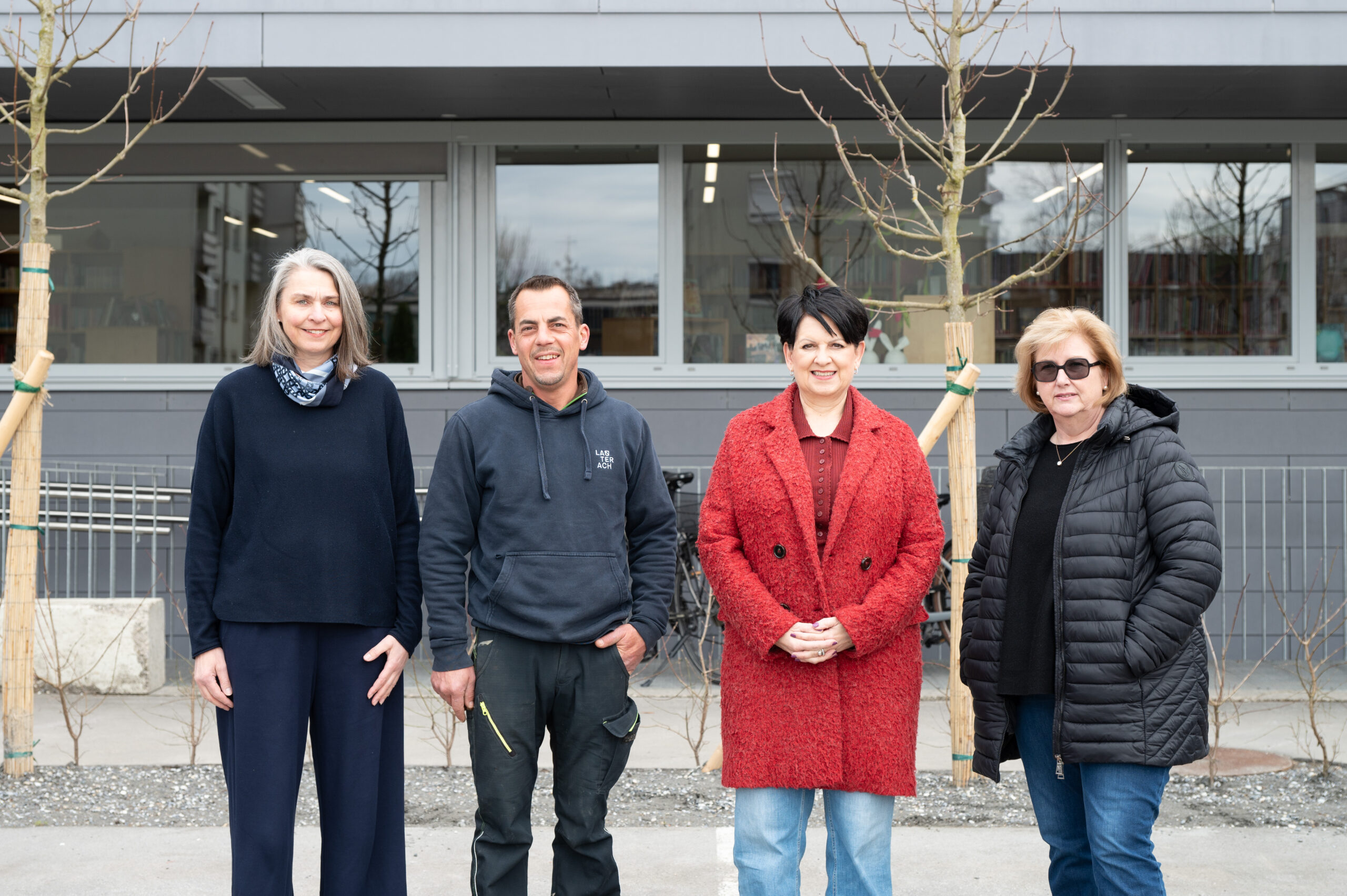 Das Bild zeigt eine Gruppe von vier Personen, die in die Kamera lächelnd vor der Bücherei Lauterach stehen.