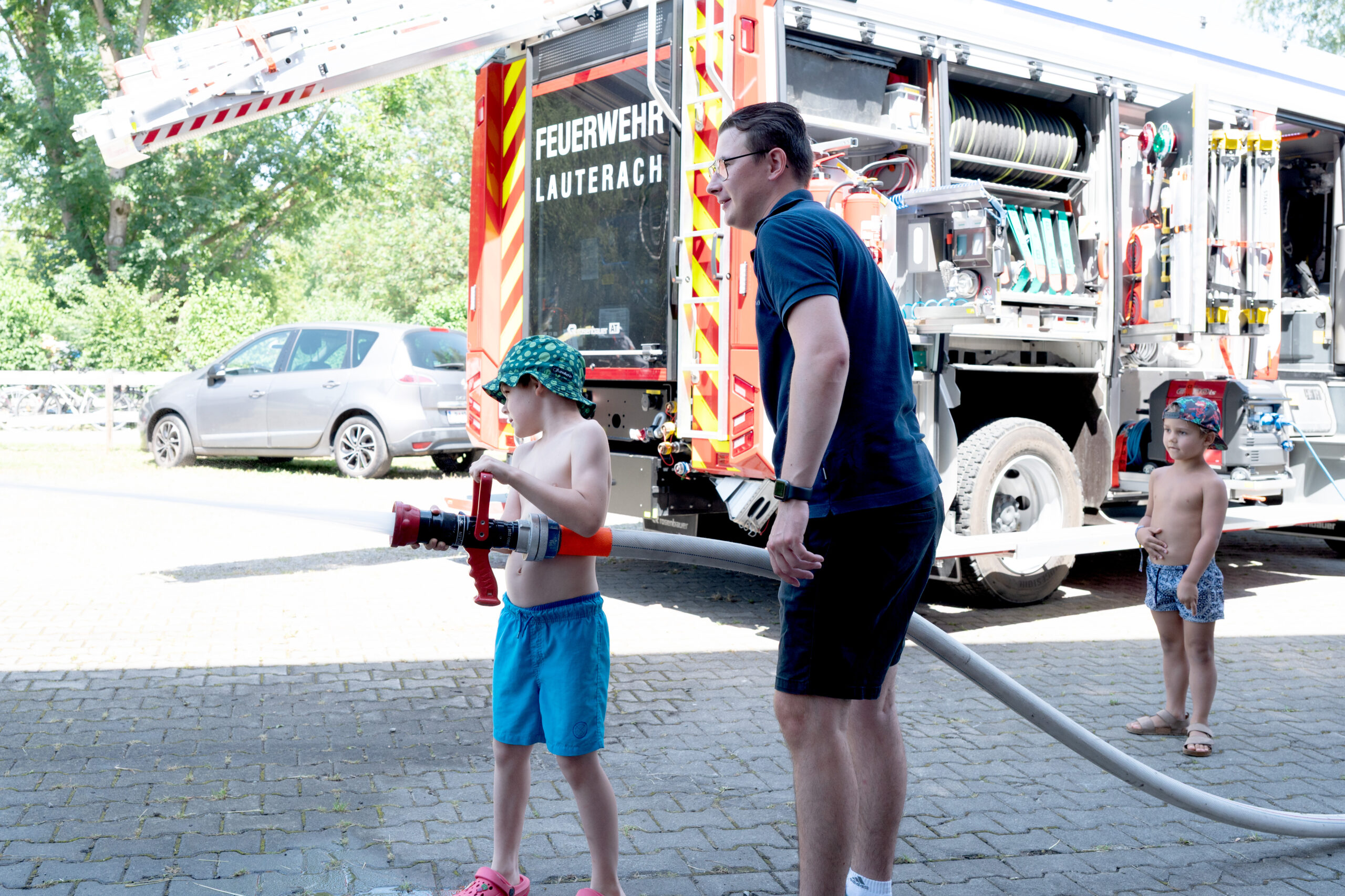 Kinder mit Feuerwehrschlauch und Feuerwehrwagen