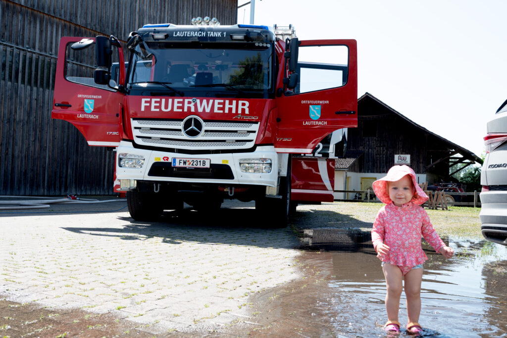 Kind steht vor Feuerwehrfahrzeug.