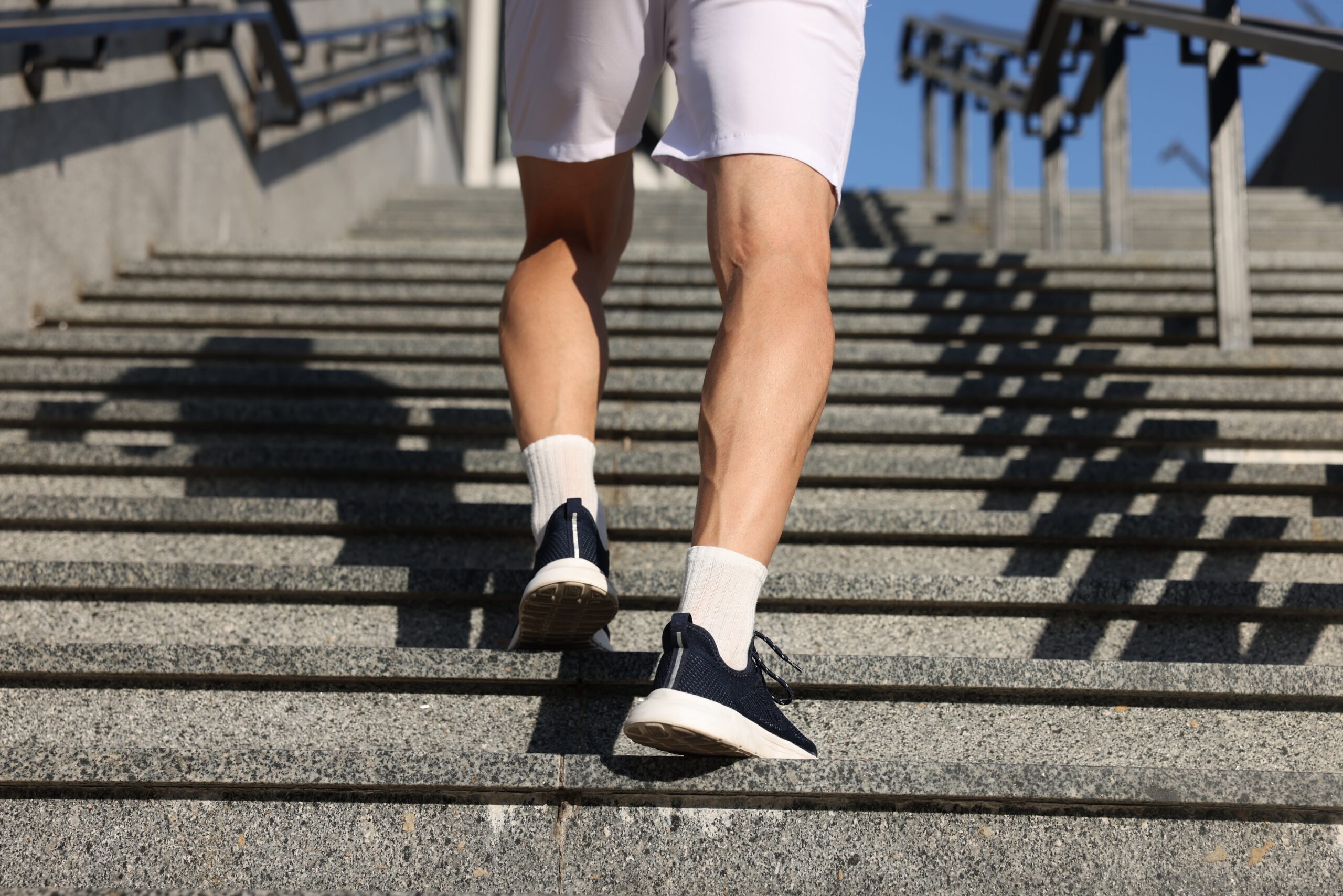 Muskulöse Beine eines Mannes mit Sneakers beim Treppensteigen