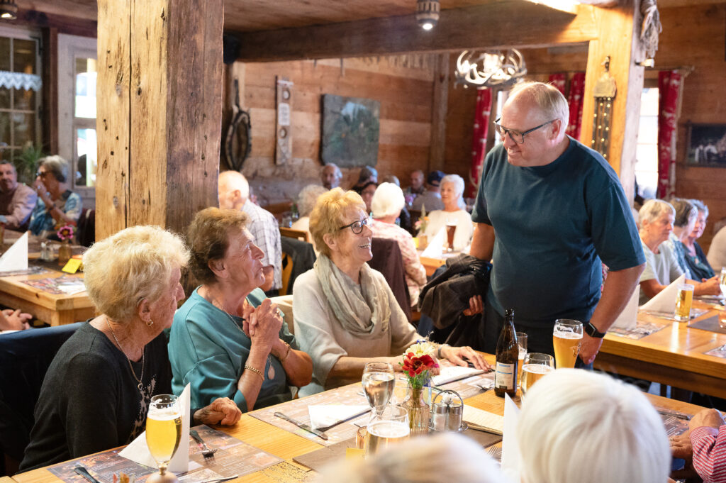 Der Lauteracher Bürgermeister Elmar Rhomberg steht vor einem Tisch mit mehreren Besucherinnen und hört einer der Frauen beim Sprechen zu.