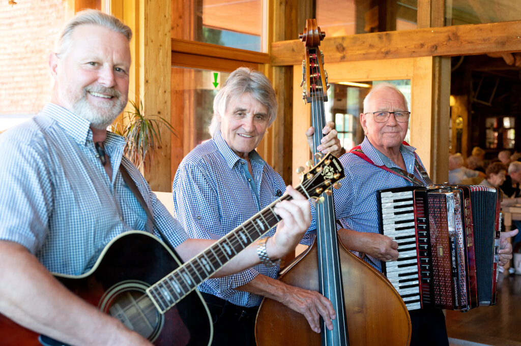 Das Band-Trio steht mit Gitarre, Handorgel und Kontrabass und blickt in die Kamera.