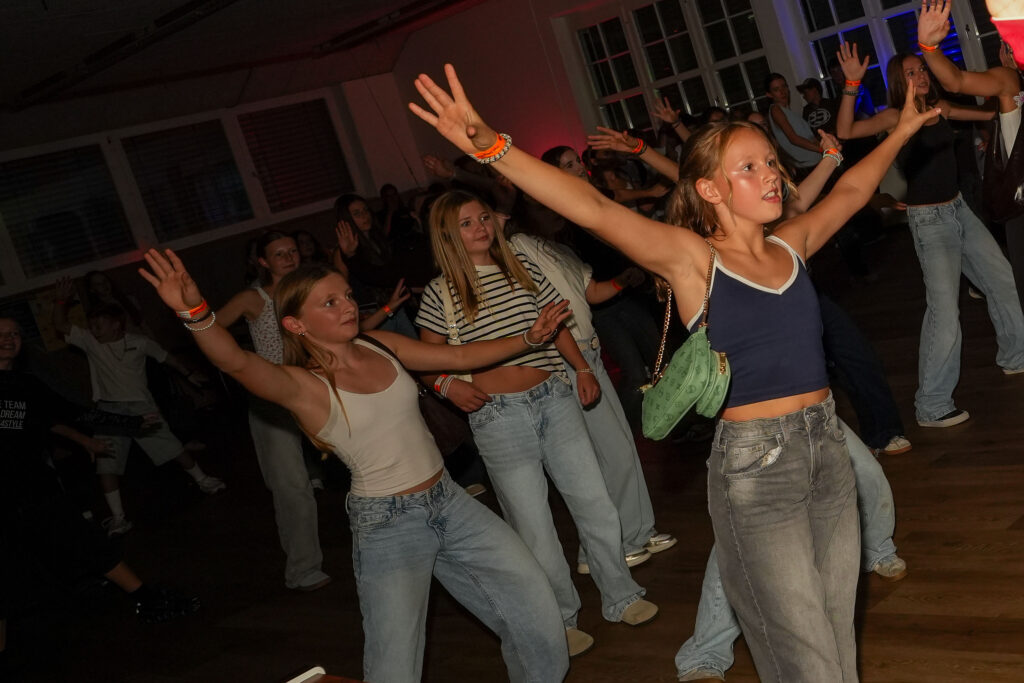 Tanzende Jugendliche mit ausgestreckten Armen beim Jugend-Clubbing in der Säge.