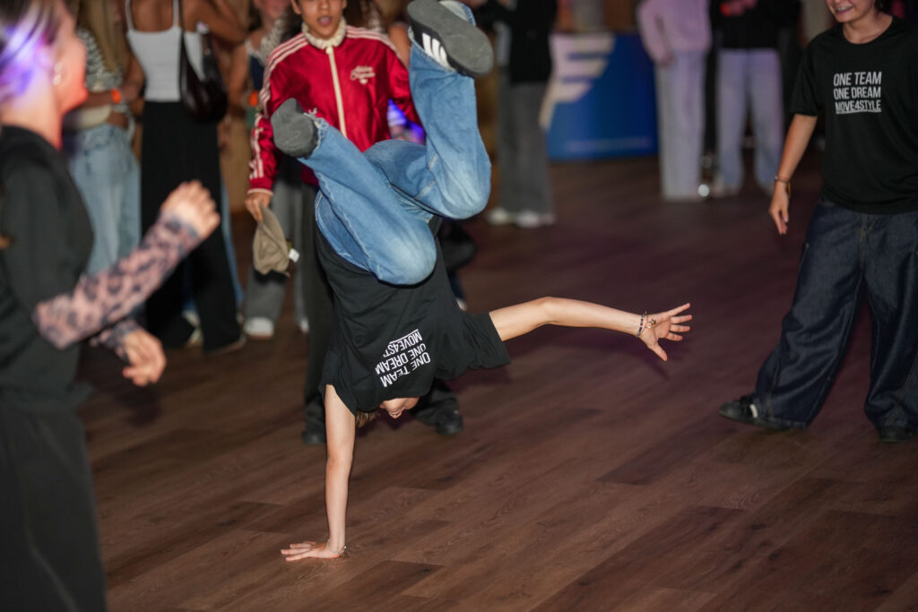 Ein Mädchen tanzt Breakdance und macht einen Handstand auf einer Hand.