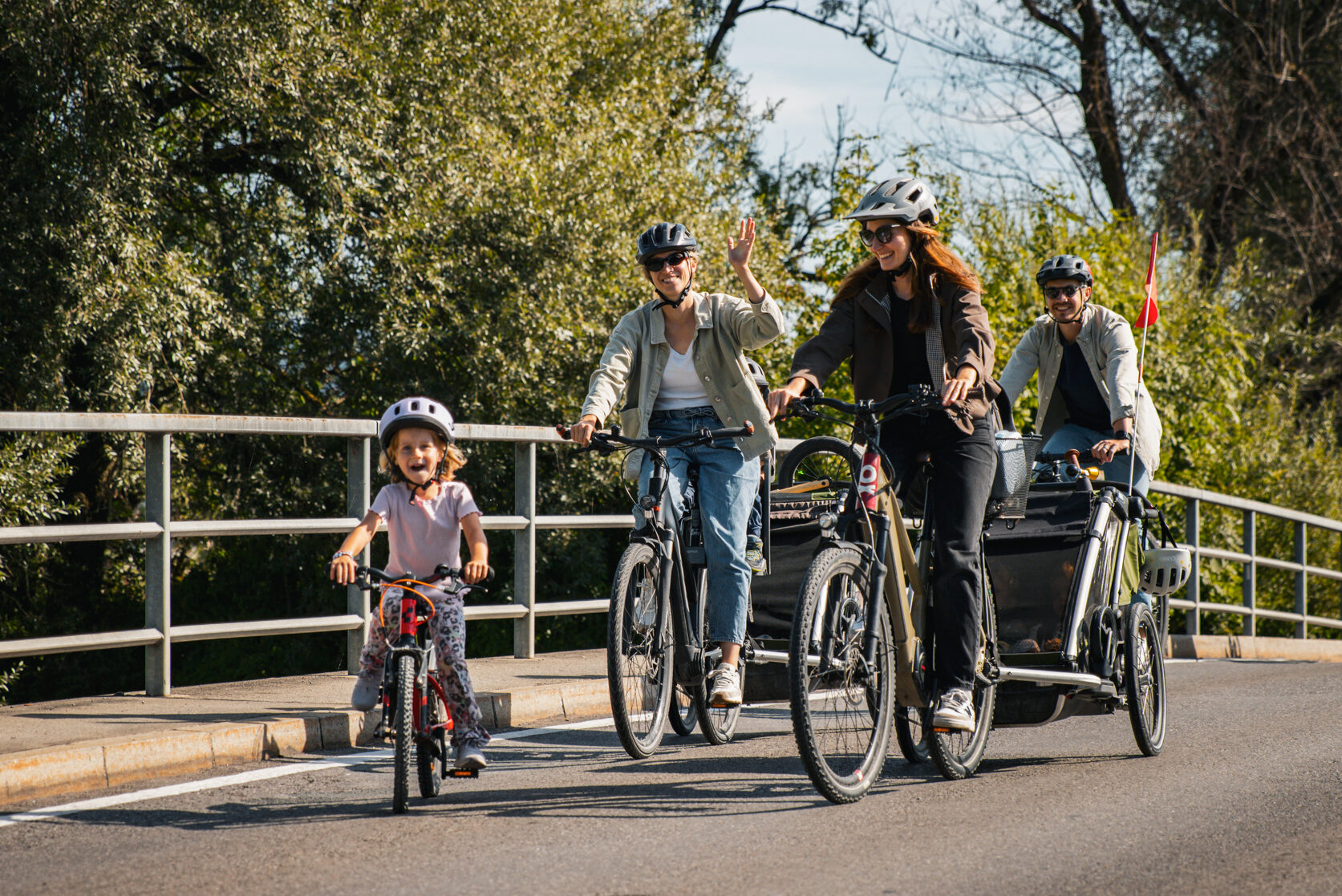 Drei Erwachsene und ein Kind auf Fahrrädern auf einer Brücke
