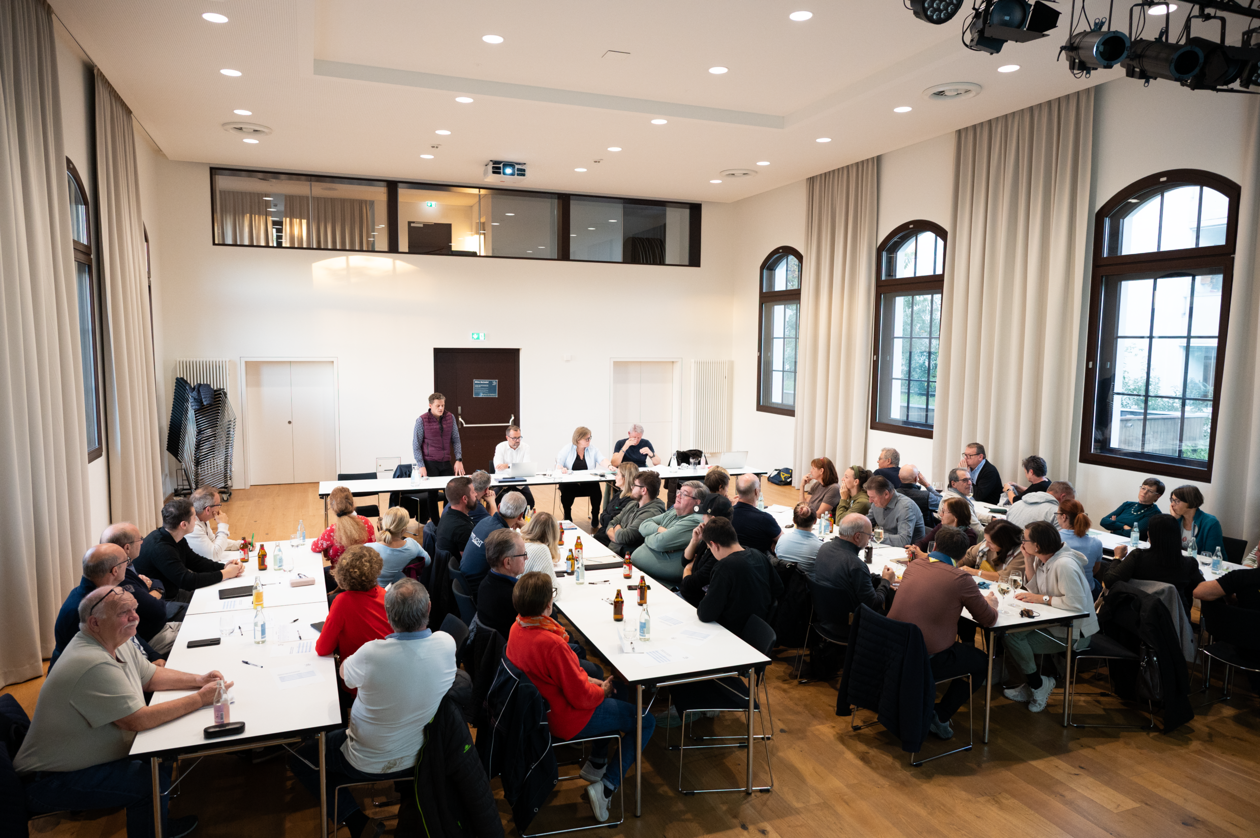 Viele Menschen an mehreren Tischreihen.