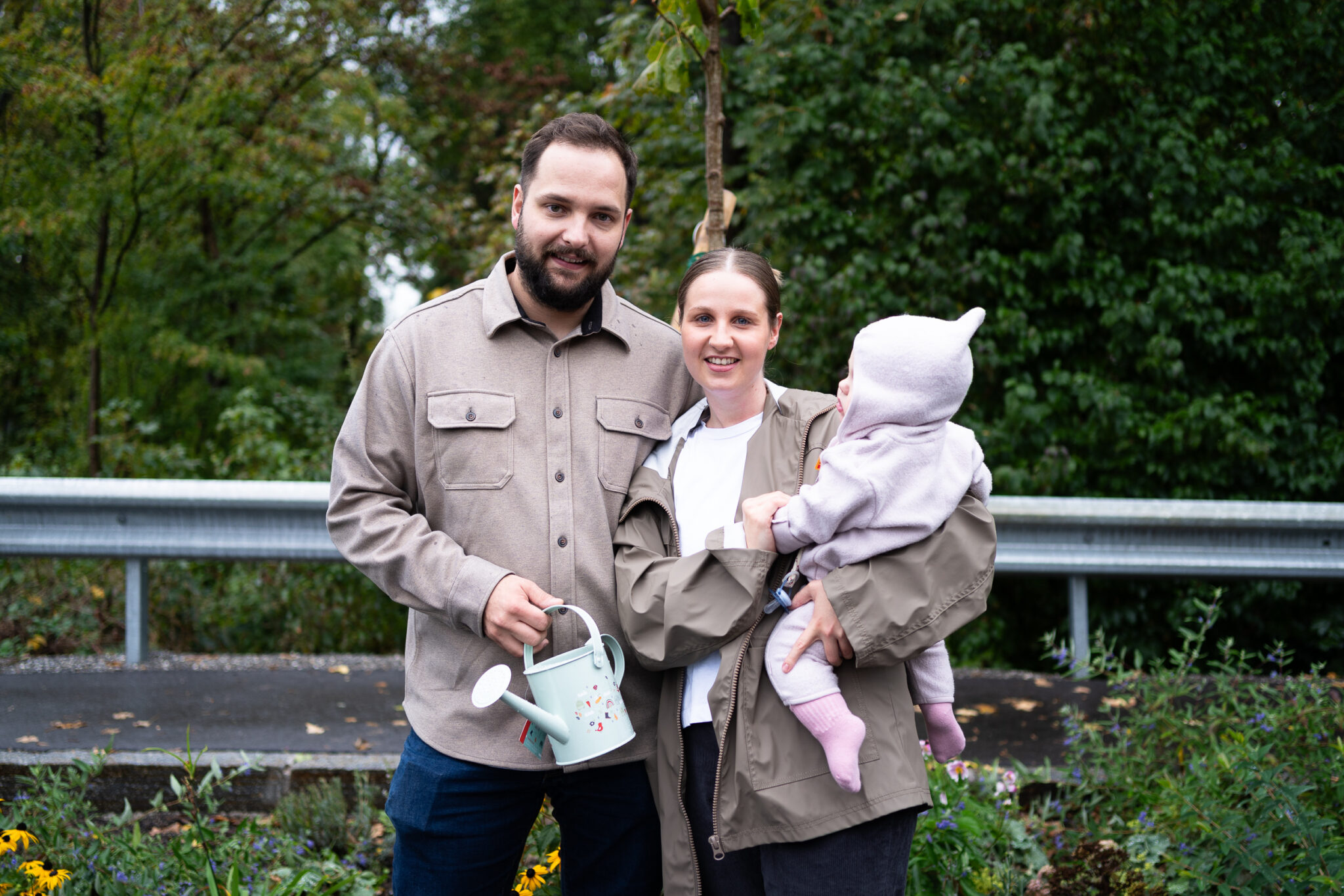 Familie mit Baby und Gießkanne im Garten