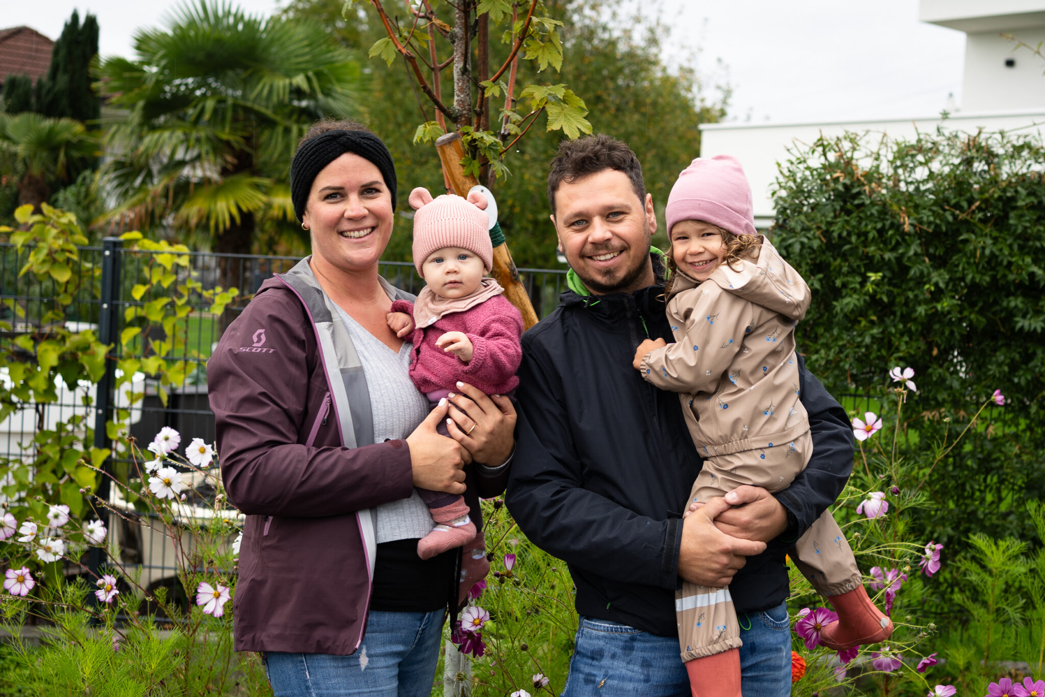 Familie mit zwei Kindern posiert im Garten vor einem Haus